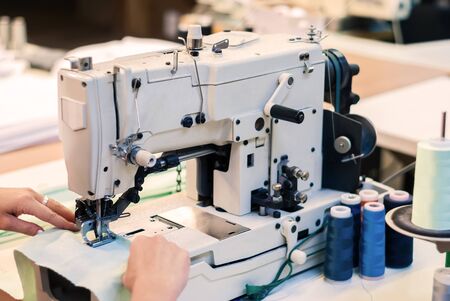 industrial overlock sewing machine and hands of seamstress at work in the garment factoryの写真素材