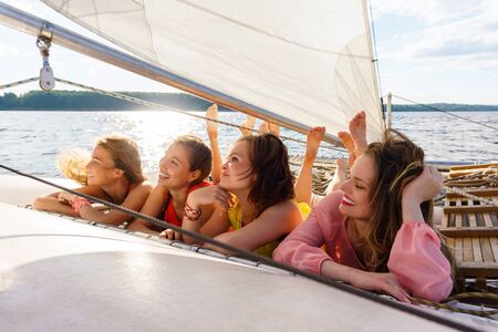 four young women relaxing on a sailing yachtの写真素材