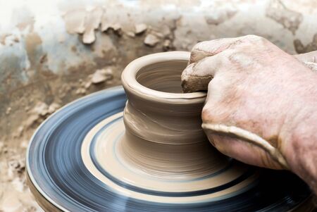 men's hands making a clay mug on a potter's wheel