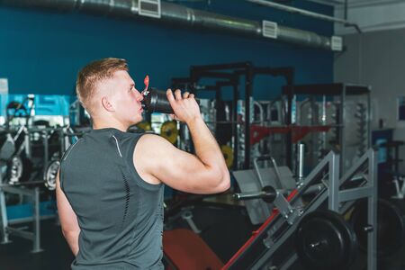 athlete drinking from a shaker botle for sports nutrition in the background of the gym
