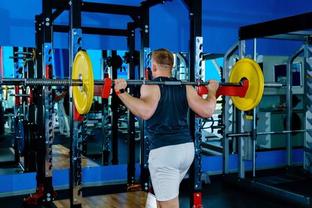 athlete performs a squat barbell next to the weight machine in the gym