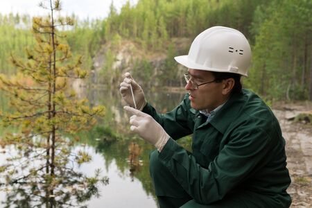 industrial ecologist or chemist takes a sample of water from a flooded quarryの写真素材