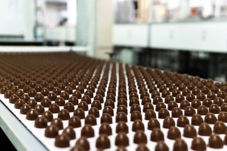 rows of toppings for chocolates manufactured by machine, on a conveyor of a chocolate factory の写真素材