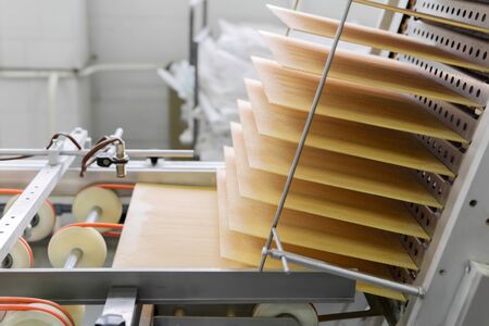 freshly baked wafer sheets rise along the conveyor of a confectionery factoryの写真素材