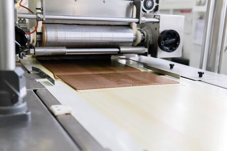pouring wafer sheets with a thin layer of chocolate on the conveyor of a confectionery factory