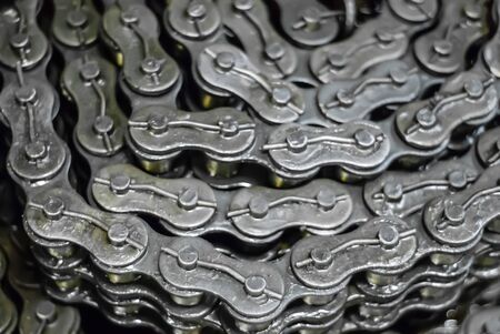 blurred industrial background - oiled rolled-up drive chains for heavy equipment in stock