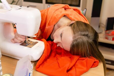 woman dressmaker is trying to independently install a needle in a sewing machine