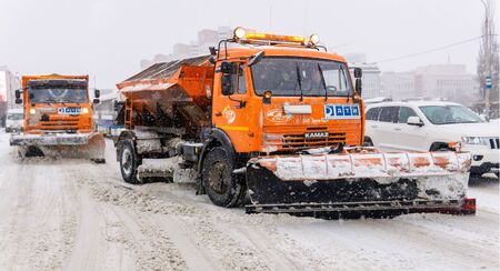 Perm, Russia - December 24, 2019: working truck mounted snow plows on a road during heavy snowのeditorial素材