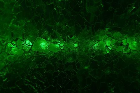abstract dark green background - a series of lights shine through cracked ice