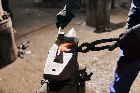 blacksmith forges a horseshoe on the anvil with forging chisel, close-upの写真素材