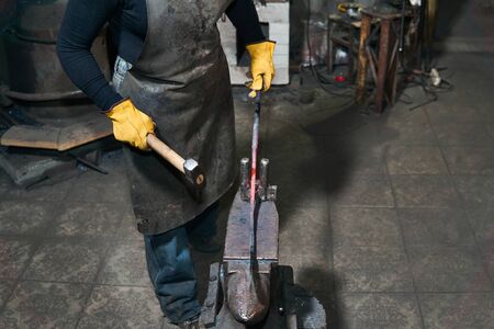 female hands forge a hot metal workpiece on the anvil in a traditional forge