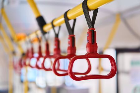 interior elements of public transport - city bus grab handles for standing passengers - on a blurred...