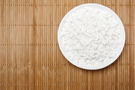 bowl with grainy cottage cheese on a straw tablecloth mat, top viewの写真素材