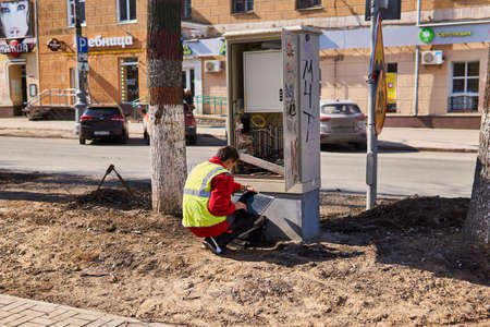 Perm, Russia - April 15, 2020: communications engineer is repairing something in a wired telecommunications network distribution cabinet on a deserted street during quarantineのeditorial素材