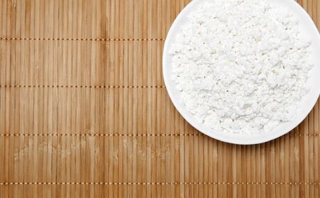 bowl with grainy cottage cheese on a straw tablecloth mat, top viewの写真素材