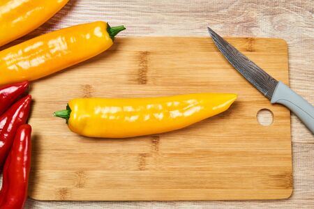 still life with yellow and red pods of sweet pepper and kitchen knife on a cutting board の写真素材
