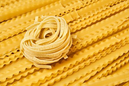 dry pasta tagliatelle and mafaldini warm backgroundの写真素材