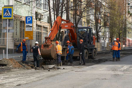 Perm, Russia - May 05, 2020: workers gathered around an excavator discuss work on the upcoming trenching on a city streetのeditorial素材