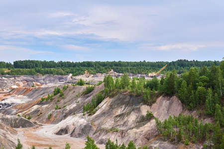 multi-colored clay hills and ravines on the site of an old kaolin quarry, the excavator is visible in the distanceの写真素材