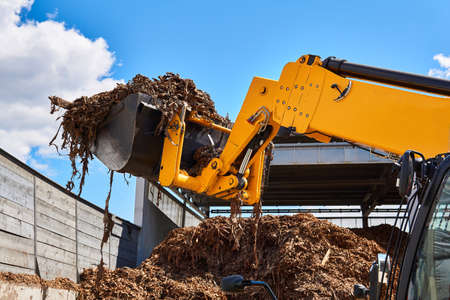 bucket loader moving wood bark in a woodworking industry