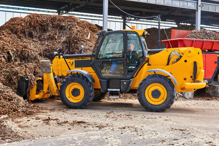 bucket loader loads wood bark into an industrial tree chipper in a woodworking industry