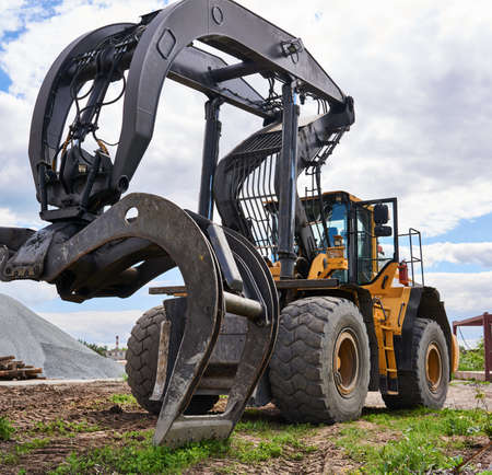 indusrtial dual function grapple skidder stands on the ground outdoors