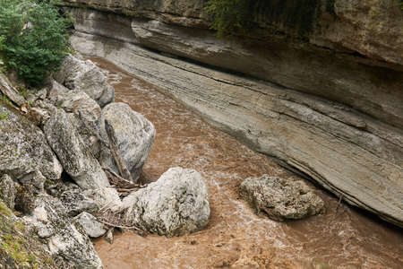mountain canyon with stones that fell into a muddy river during flooding after rains