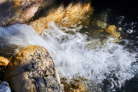fast clean seething mountain stream among rocks blurred in motionの写真素材