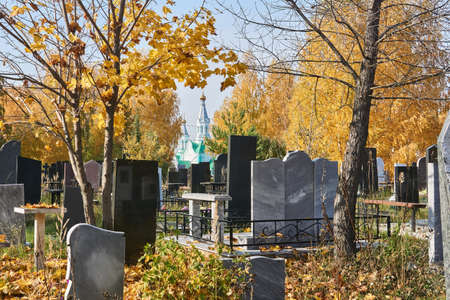 autumn cemetery overgrown with trees overlooking the orthodox church