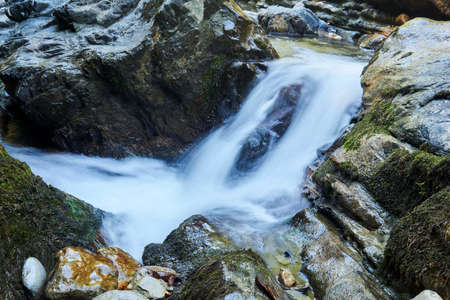small waterfall in a mountain stream between rocks, water jets are blurred in motion