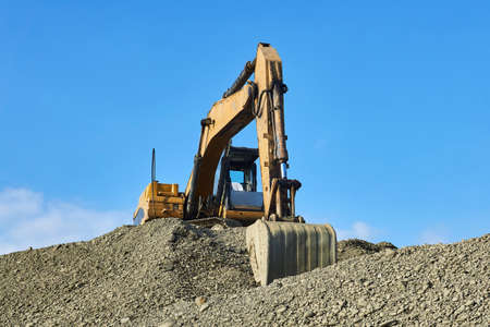 excavator has finished work and is standing on a pile of rubble against the background of the sky