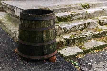 antique wooden barrel for collecting rainwater stands by the porch