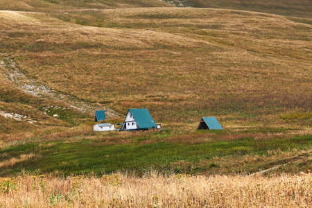 alpine tourist shelter in the autumn mountains against the background of dry alpine meadowsの写真素材