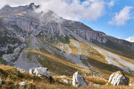 landscape with a mountain peak in the clouds and huge white boulders in the foreground