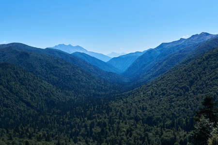 wide river valley between wooded mountains stretches to the horizon in a blue haze