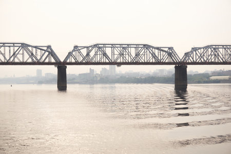 road bridge over a wide river and the silhouette of a distant city behind it in the morning hazeの写真素材