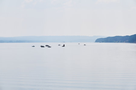 fishermen on inflatable boats fish on a calm wide river in the morning fogの写真素材