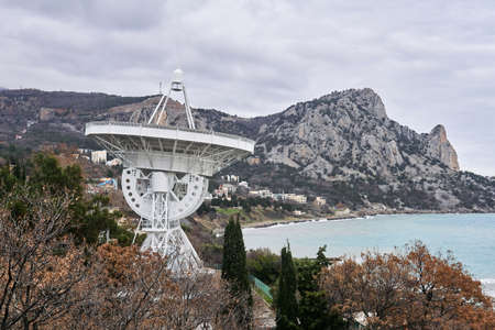 large astronomical radio telescope on the seashore against the backdrop of mountainsの写真素材