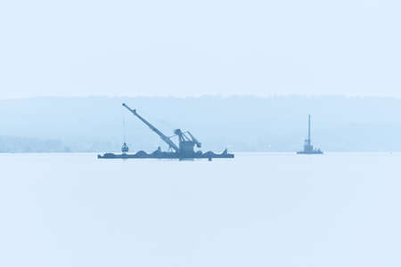 dredging boats is working to deepen the fairway on the river in the morning fogの写真素材