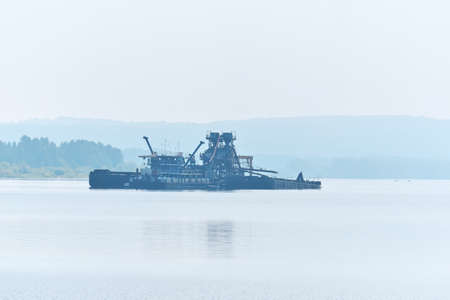 floating sand mining plant working on the river in the morning fog