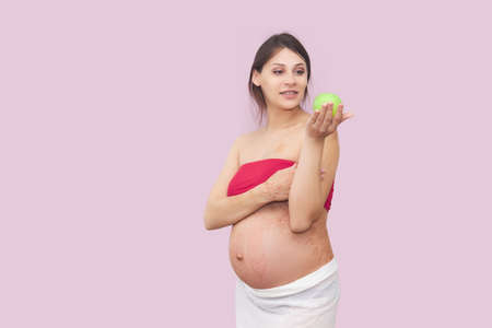young pregnant woman holds a ripe green apple