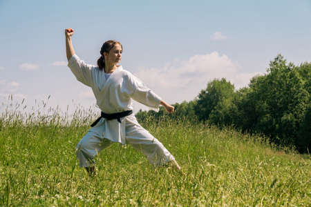 teen girl performing karate kata outdoors in kokutsu-dachi stanceの写真素材