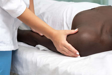 woman masseuse doing massage of shoulder area of hand to black manの写真素材