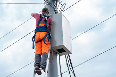 Perm, Russia - August 25, 2021: electrician or telecommunications lineman works on laying a cable at...