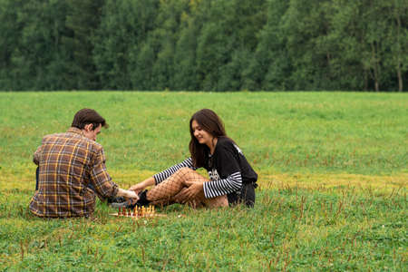 Perm, Russia - August 23, 2021: two young people play chess on the lawn in the park