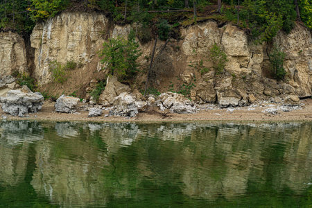 wooded river bank with crumbling marble cliffs, water erosion of coastal rocks