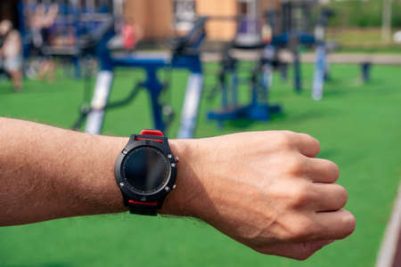look at a smartwatch on a man's hand against the background of outdoor gym machines