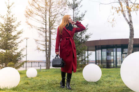 young woman walks on the lawn in the autumn coastal park among the round lampsの写真素材
