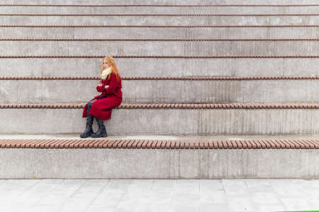 sad young woman sits alone in empty standsの写真素材