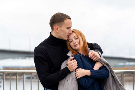 couple in love, the guy puts his jacket on the girl's shoulders in cold weatherの写真素材